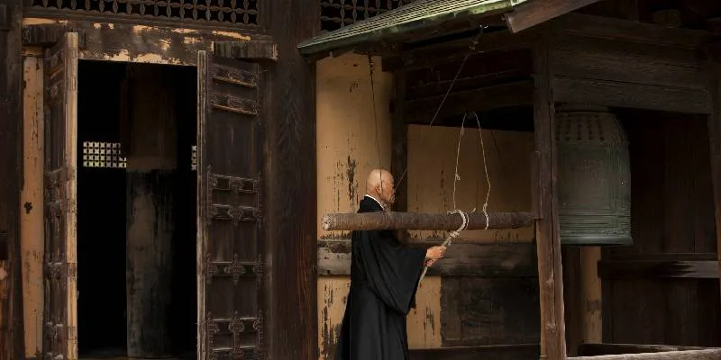 Un monaco buddista suona una campana in un monastero a Kamakura.