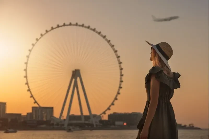 Donna che ammira il tramonto e la vista sulla ruota panoramica Ain Dubai, Emirati Arabi Uniti.