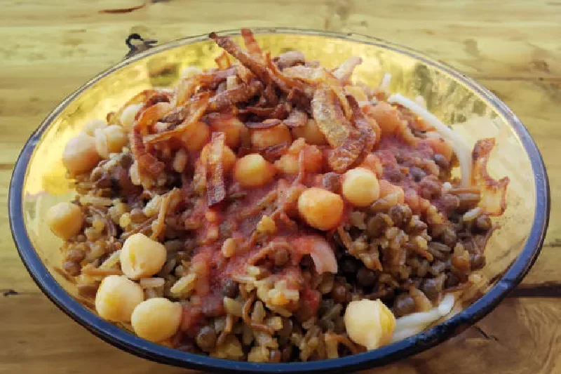 Koshari, das traditionelle ägyptische Nationalgericht aus Reis, Linsen, Nudeln, Tomatensauce und knusprigen Zwiebeln, serviert in einer Schale.