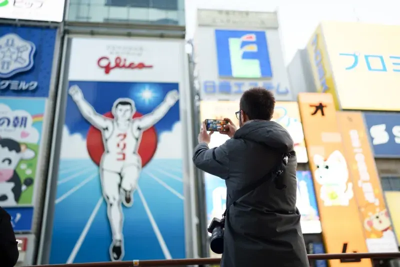 Hombre usando su teléfono móvil en Dotonbori, Osaka.