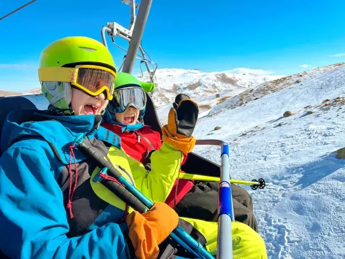 Two brothers skiing in mountain, going up on ski lift and having fun
