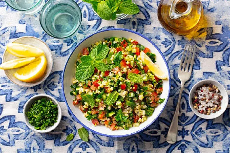 Bulgursalat mit Minze garniert, serviert mit Zitronenscheiben und Olivenöl