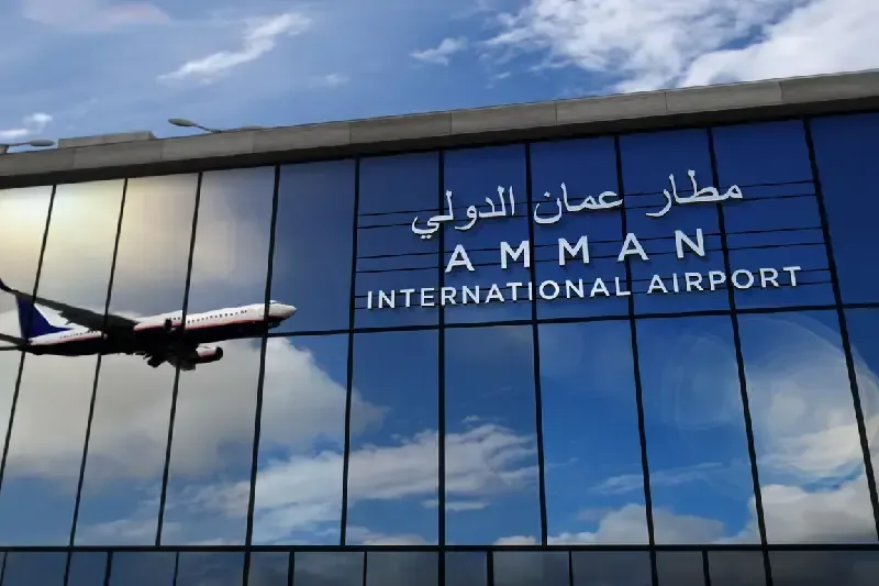 Landendes Flugzeug am Flughafen von Amman, Jordanien, gespiegelt in der Terminalfassade