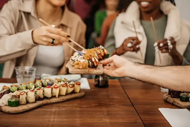 amigos-compartilhando-pratos-de-sushi-com-hashi-em-restaurante