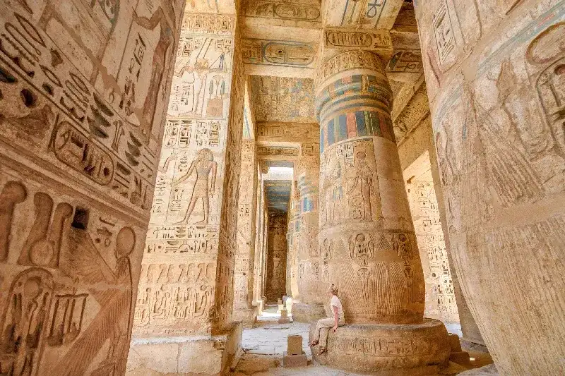 Frau sitzt auf einer Säule im Tempel von Ramses III. in Luxor, Ägypten