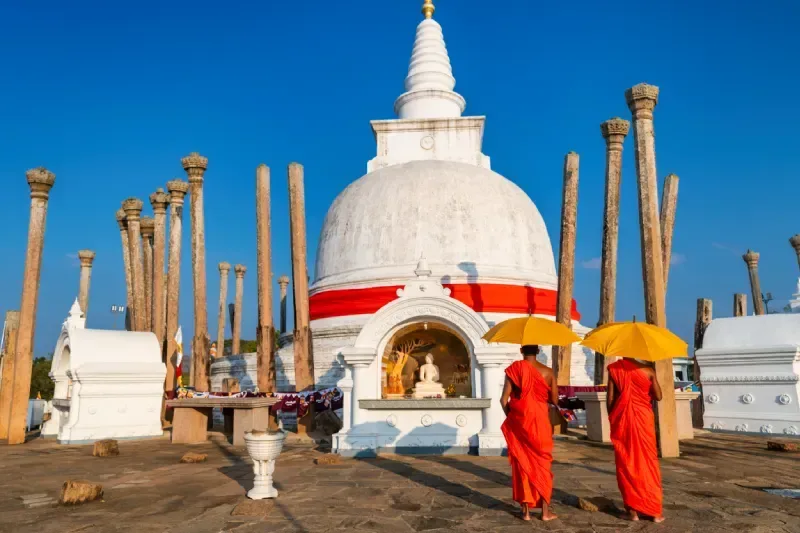 Sri Lankan buddhist monks walking inside an ancient temple near Anuradhapura