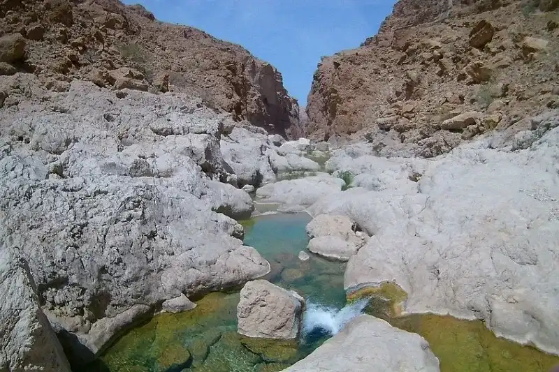 Wadi Al Arbaeen con piscine naturali d'acqua verde smeraldo incastonate tra rocciosi canyon dorati.