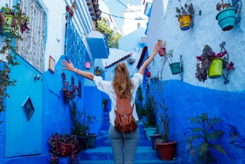 Mujer turista feliz en la calle azul de Chefchaouen