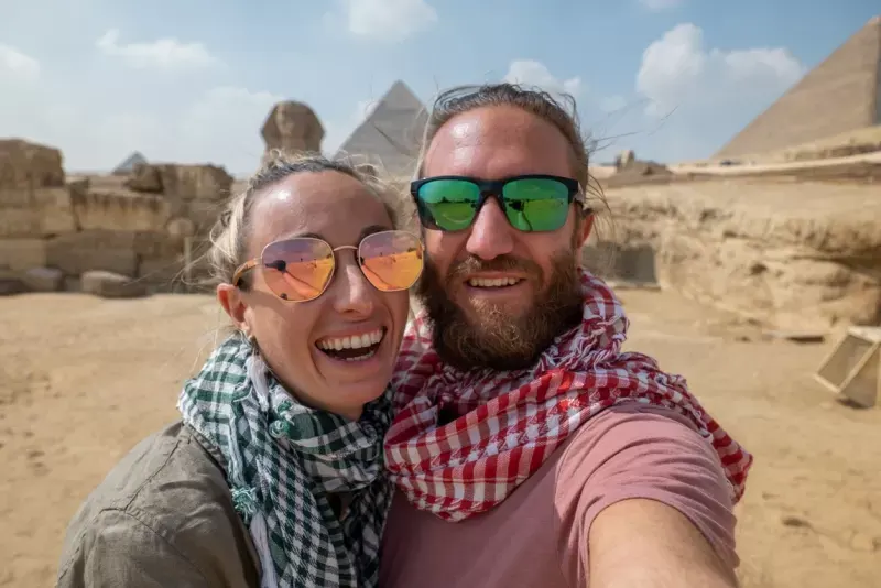 Pareja feliz tomando selfie frente a las Pirámides de Guiza