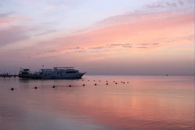 Rosa Sonnenuntergang über dem Roten Meer in Ägypten mit Booten auf dem Wasser und warmem Sonnenlicht