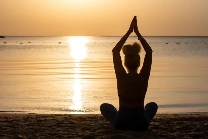 Donna che fa yoga sulla spiaggia del Mar Rosso al tramonto
