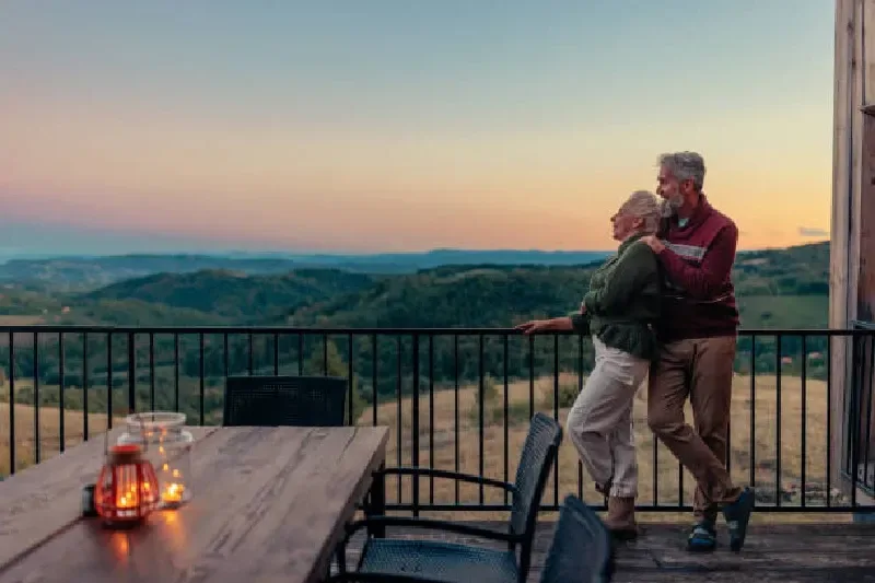 Älteres, pensioniertes Paar genießt einen entspannten Aufenthalt in den Bergen mit Aussicht auf die Landschaft.