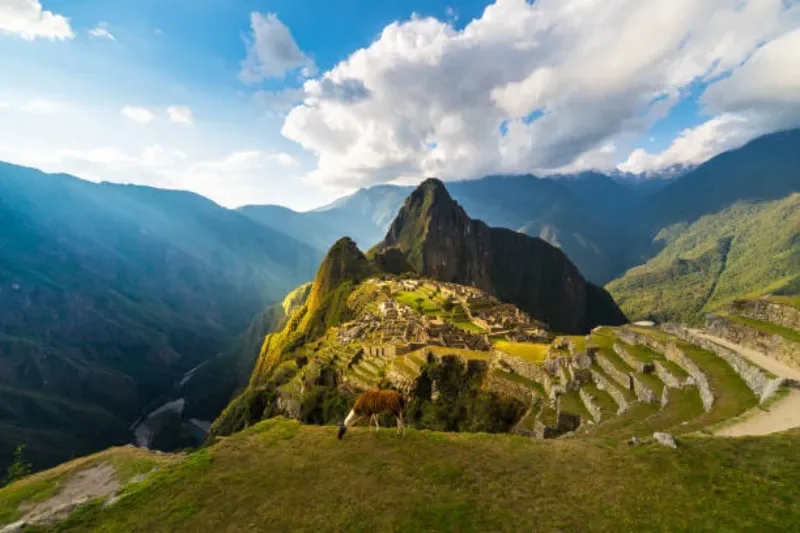 Machu Picchu im warmen Licht des Sonnenuntergangs, Weitwinkelaufnahme von den Terrassen mit beeindruckendem Himmel, Cusco, Peru