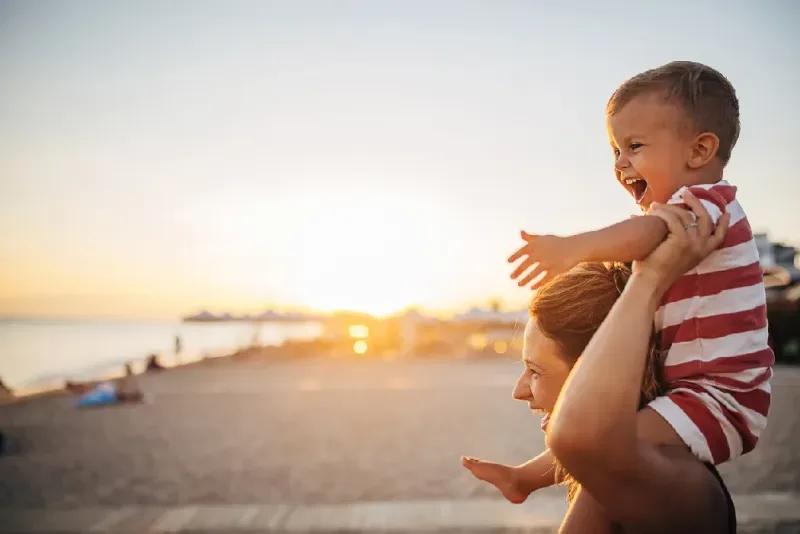 madre-llevando-a-su-hijo-en-la-playa