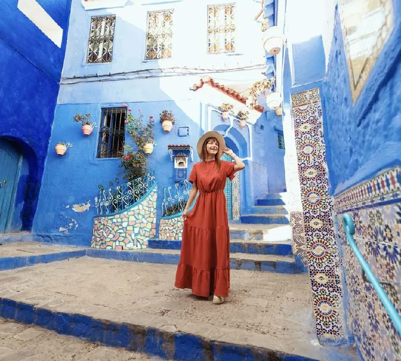 Jovem mulher com vestido vermelho visitando a cidade azul de Chefchaouen, Marrocos - Turista feliz caminhando nas ruas da cidade marroquina - Conceito de estilo de vida de viagens e férias