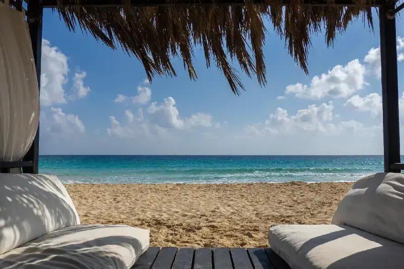 Ein eleganter Pavillon am ruhigen Strand von Marsa Matruh in Ägypten mit tropisch blauem, türkisfarbenem und grünem Meerwasser des Mittelmeers. Entspannte Urlaubsatmosphäre ohne Menschen am Strand.