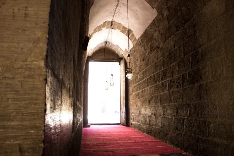 Führer zeigt auf die kunstvoll geschnitzte Minbar im Qibla-Iwan der Sultan-Hassan-Moschee