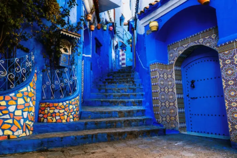 Blick auf die charakteristischen blauen Häuser und engen Gassen der Chefchaouen, mit farbenfroher Architektur, Treppen und Fenstern, die den einzigartigen Charme der Stadt in Morocco zeigen.