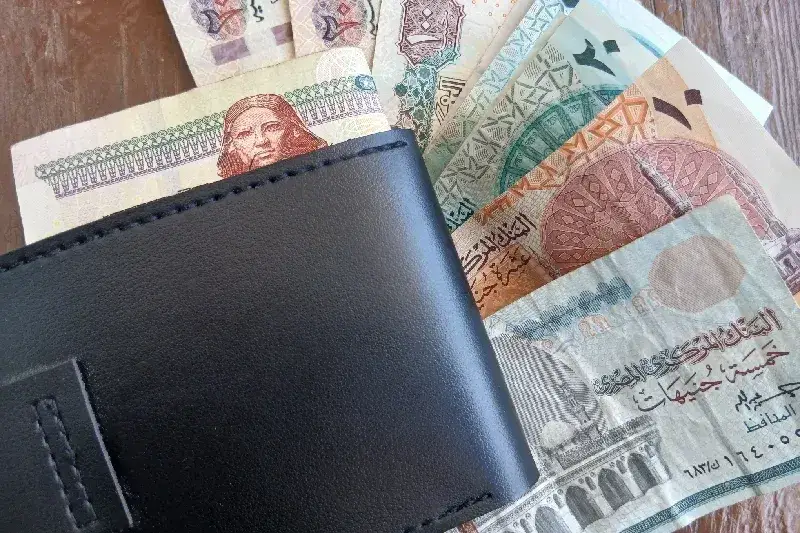 Schwarze Geldbörse mit teilweise sichtbaren ägyptischen Geldscheinen, die persönliche Finanzen, Budgetplanung, Sparen, Bargeldverwaltung und alltägliche Zahlungsvorgänge in Ägypten darstellen.