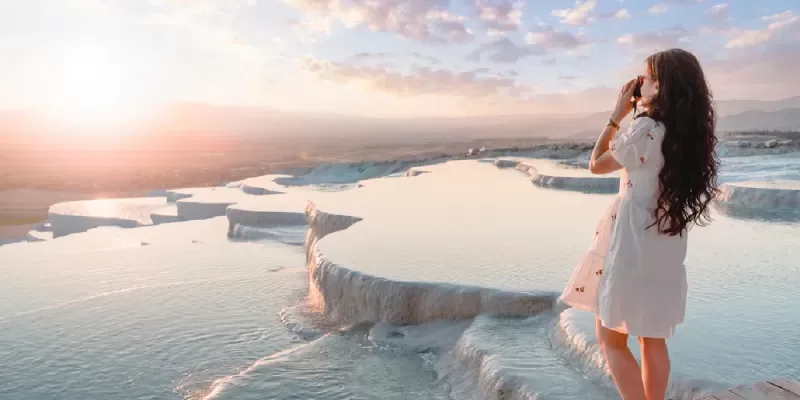 Traveler capturing sunset shots at Pamukkale’s travertine pools, natural wonders in Turkey.