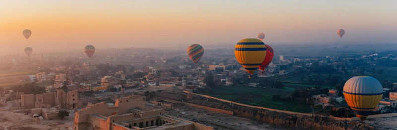 Globos aerostáticos se desplazan por un cielo dorado al amanecer sobre las antiguas ruinas de Medinet Habu, en Luxor.