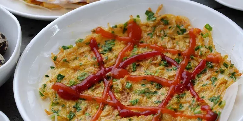 Bánh tráng nướng, un popular aperitivo vietnamita elaborado con papel de arroz, cebolla, camarón, salchicha, huevo de codorniz y salsa picante. También es conocido como la ‘pizza vietnamita’.