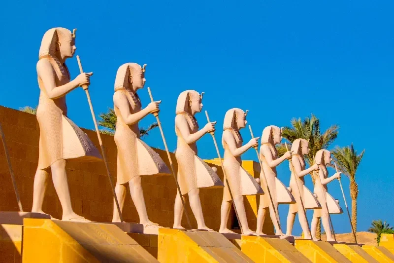 Ägyptische Kriegerstatuen vor blauem Himmel entlang einer Prozessionsroute aufgestellt