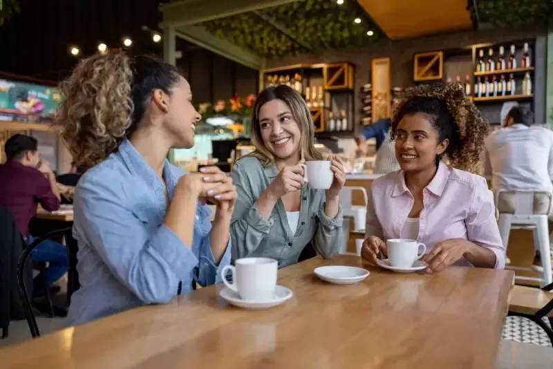 Happy group of female friends talking at a coffee shop