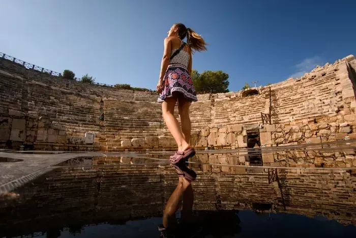 Woman walks at ruins of amphitheatre and assembly hall ancient Lycian city Patara