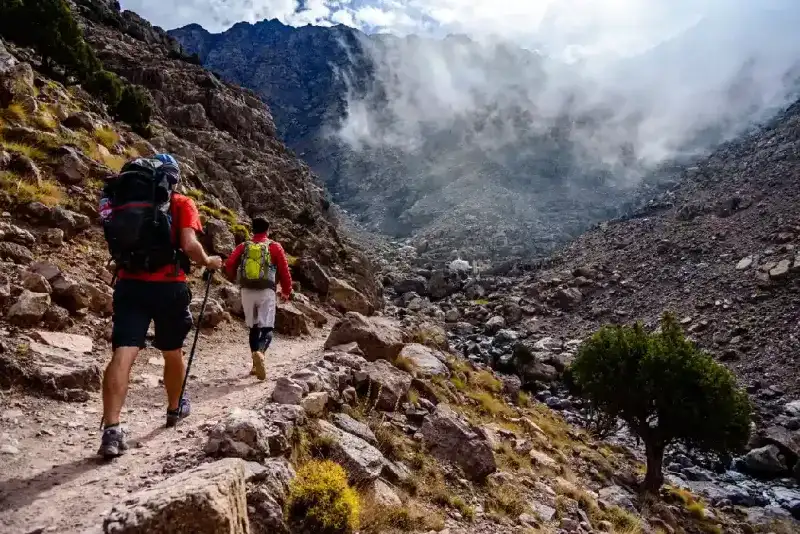 Turista haciendo senderismo hacia la cima del Jabal Toubkal, la montaña más alta de la cordillera del Atlas.