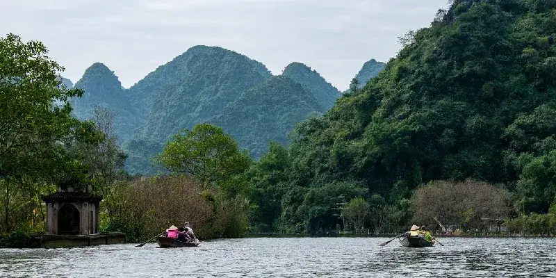 Botes que transportan a los peregrinos navegan por el río Suoi Yen, hacia la base de la colina de la zona de la Pagoda del Perfume, My Duc, Vietnam.