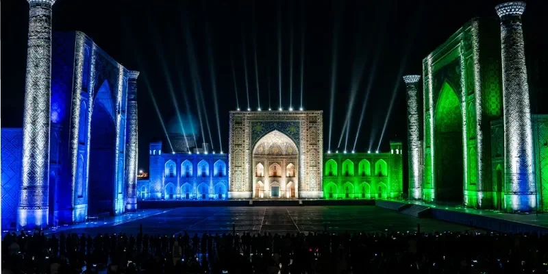 Persone che assistono allo spettacolo di luci laser in Piazza Registan a Samarcanda, Uzbekistan