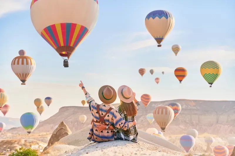 A couple admires the balloon-filled sky above Cappadocia.