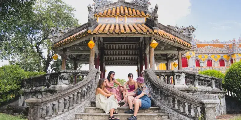 Four women sit on a pagoda’s stone steps in Hue, exploring its cultural atmosphere.