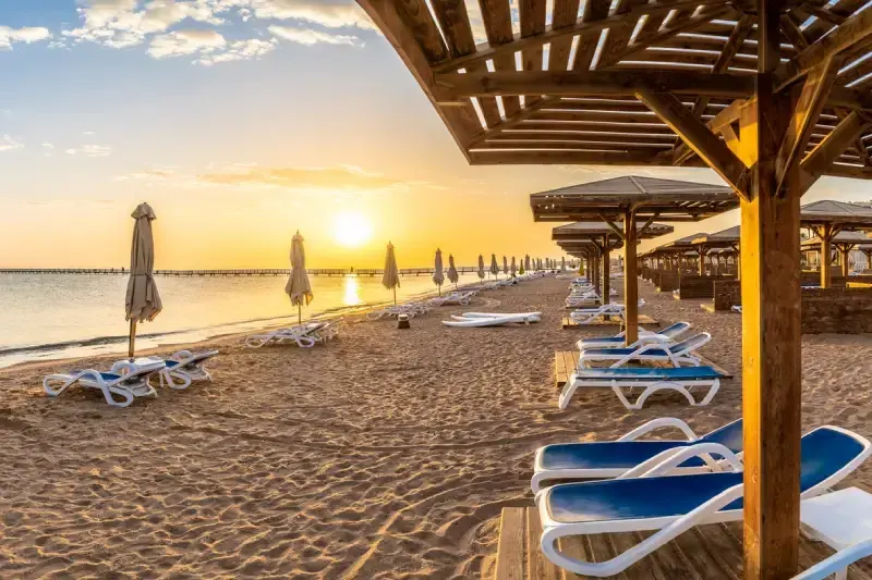 Paesaggio con lettini e ombrelloni sulla spiaggia del Mar Rosso all'alba a Hurghada, Egitto.
