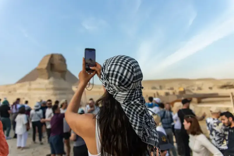 Giza, Egitto, Una turista immortala la Sfinge e le famose piramidi di Giza, nel deserto.