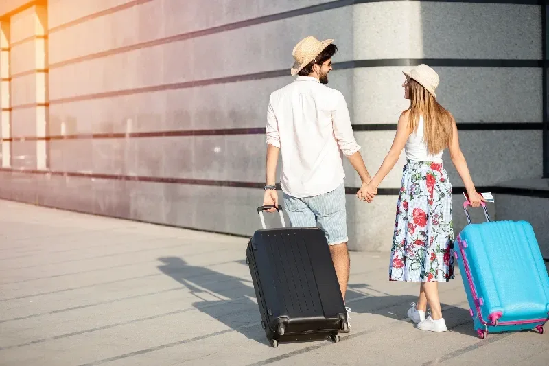Zwei glückliche junge Touristen, die Hand in Hand von der Kamera weglaufen.