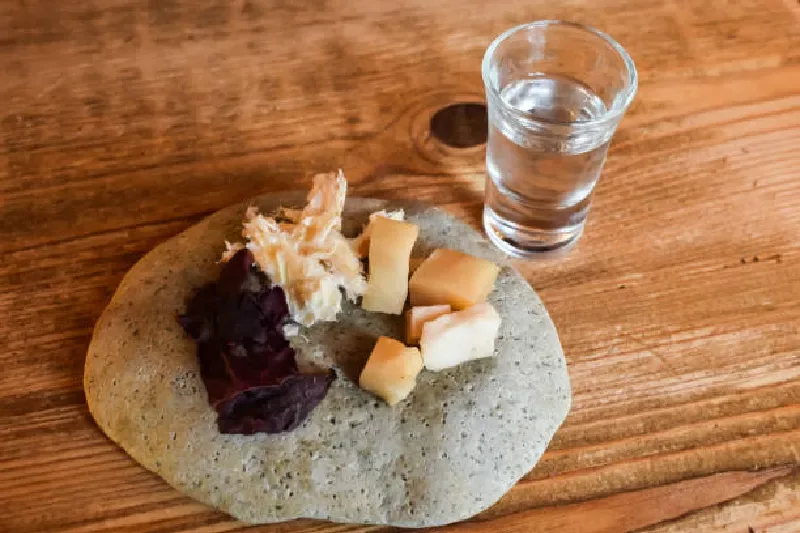 Ein traditionelles isländisches Gericht aus fermentiertem Hai, serviert zusammen mit Wodka, typisch für die lokale Küche.