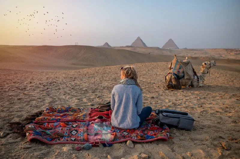 Vista trasera de una turista disfrutando de una visita a las pirámides de Guiza, en Egipto.