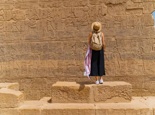 Mujer de pie frente al templo de File también conocido como templo de Isis en Asuán, Egipto.