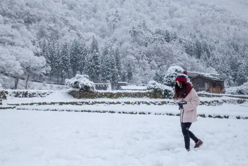 Una ragazza cammina sulla neve nel villaggio antico di Shirakawa-go