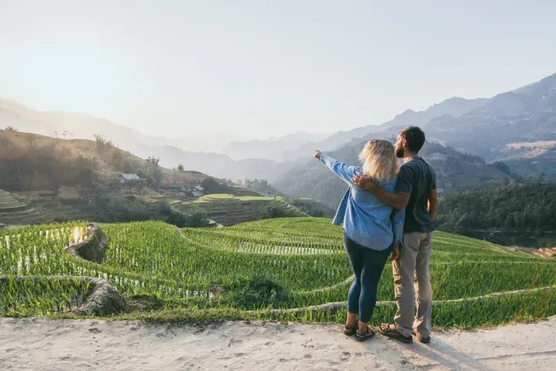 Joven pareja caucásica contemplando las terrazas de arroz de Sapa al atardecer en la región de Lao Cai, Vietnam.