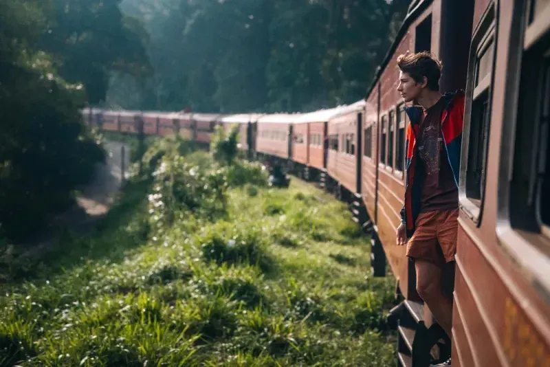 Un joven disfruta de un famoso viaje panorámico en tren a través de plantaciones de té y montañas en Sri Lanka.