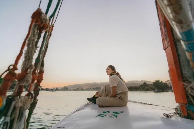 Giovane donna in viaggio su una feluca sul Nilo al tramonto