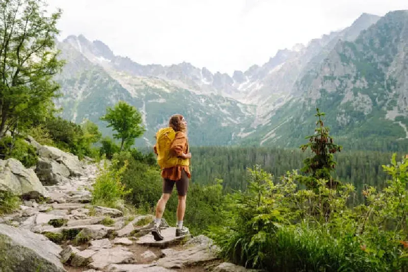 Glückliche Frau mit gelbem Wanderrucksack genießt die Berglandschaft