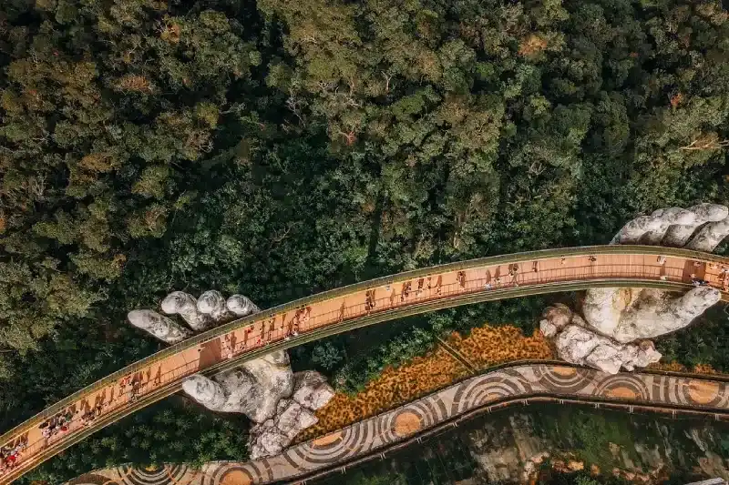 Tourists walk on the Golden Bridge in Ba Na Hills