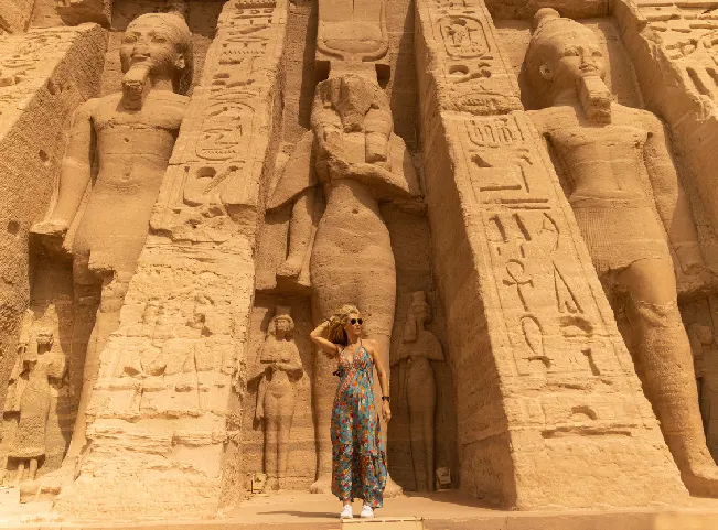 Mujer de pie frente al templo de Hathor y Nefertari dedicado a la diosa Hathor y a Nefertari, esposa de Ramsés II en Abu Simbel, Egipto.