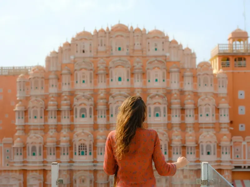 Woman looking at Hawa Mahal in Jaipur, India from balcony