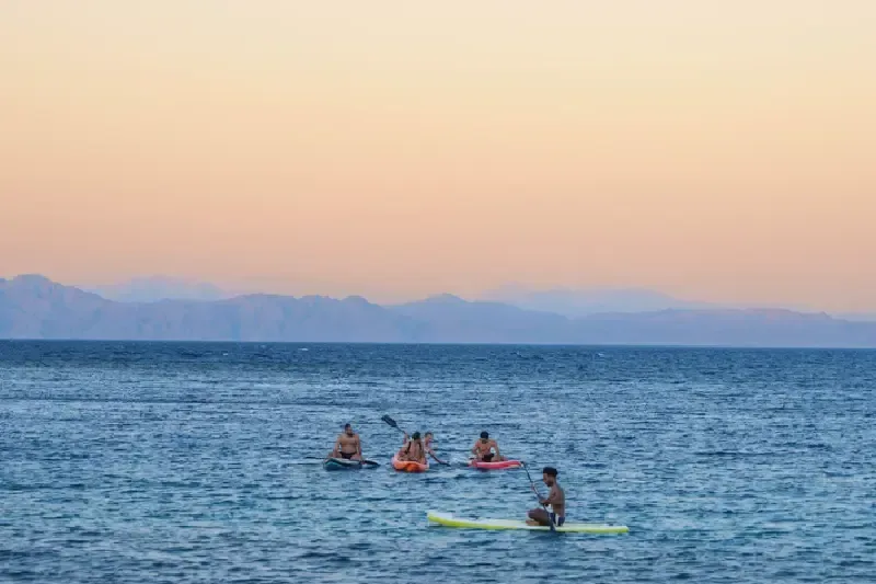Cinco personas en kayaks navegan por un mar en calma cerca de Dahab, Egipto.