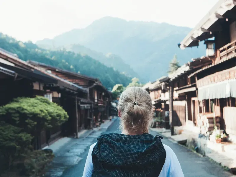 Un viajero camina con una mochila y disfruta tanto de la naturaleza como de la cultura de este hermoso entorno rural del período Edo.